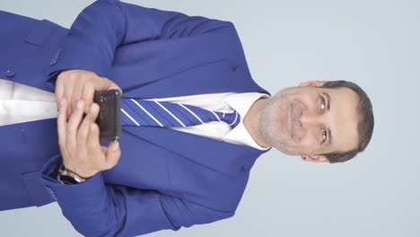 Vertical-video-of-Businessman-texting-on-the-phone.-Happy-emoticon.